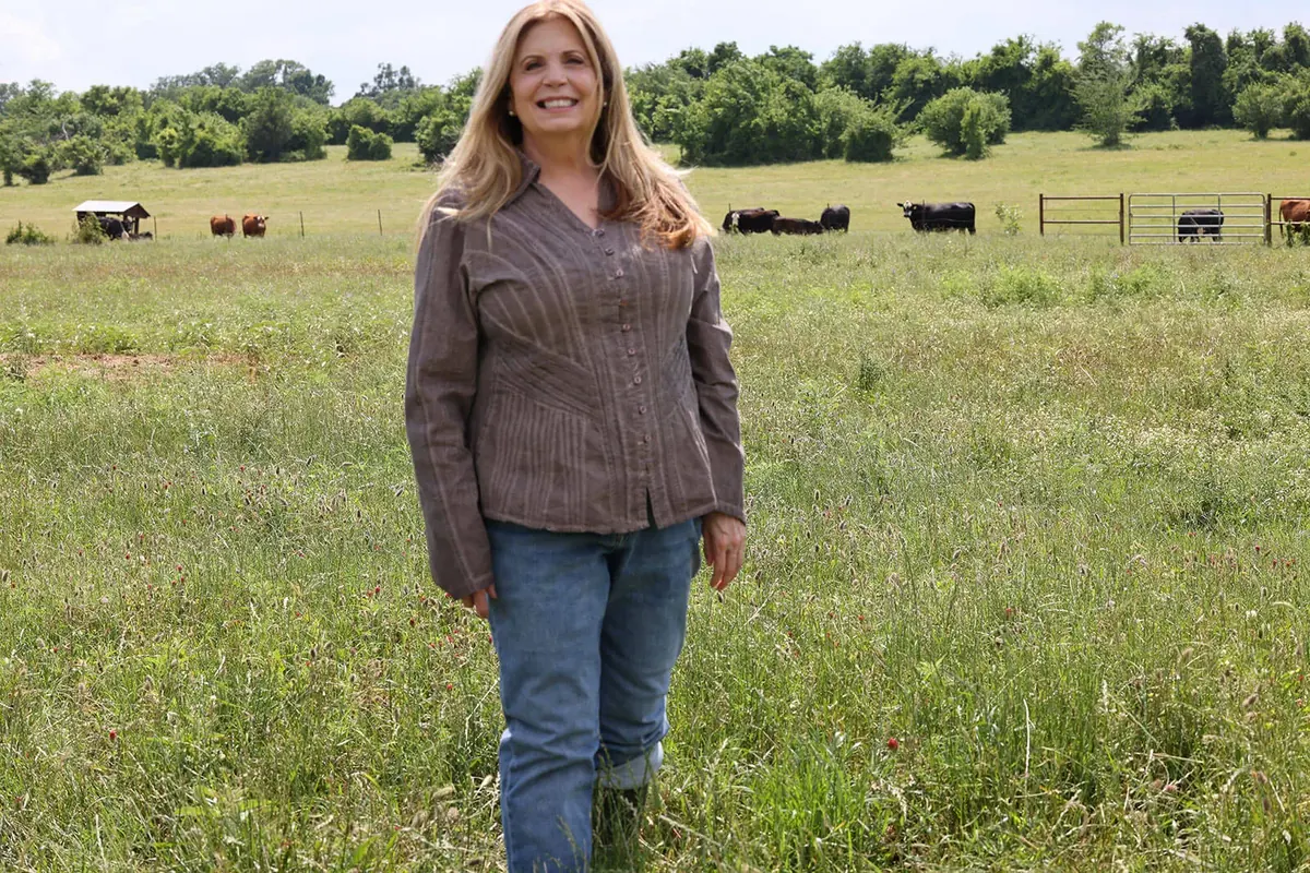 Kat Wall standing in a pasture with cattle behind her